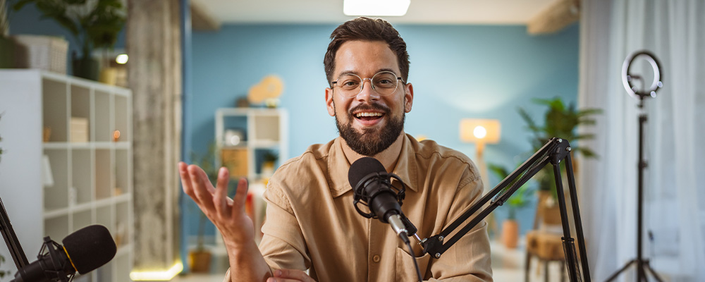 male podcaster speaking to camera with mic